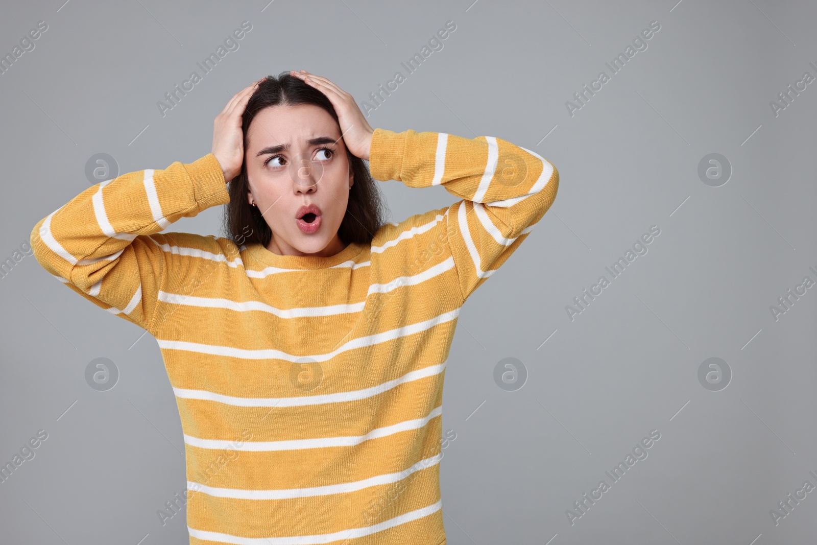 Photo of Portrait of surprised woman on grey background. Space for text