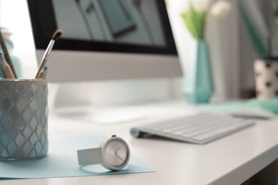 Stylish workplace with modern computer on desk, space for text. Focus on watch