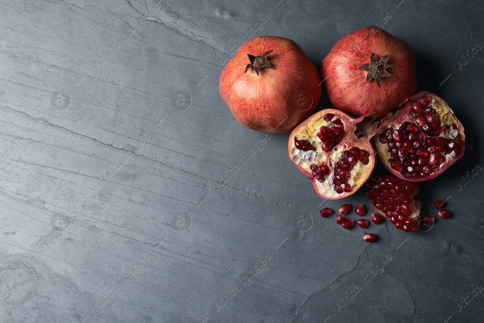 Photo of Ripe pomegranates on grey background, top view with space for text