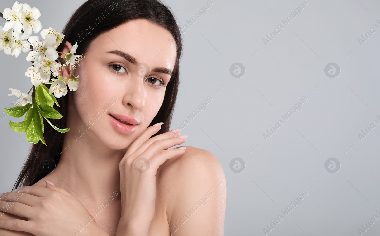 Image of Beautiful woman with smooth skin and flowers on grey background. Space for text