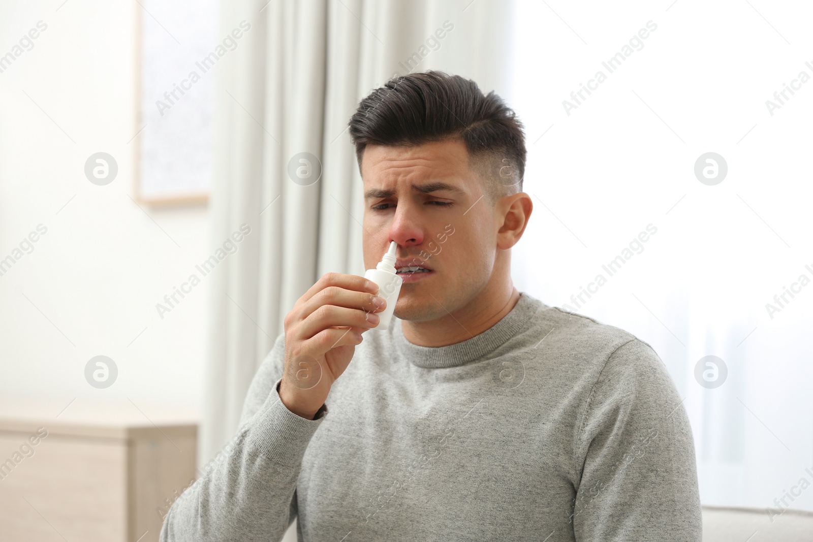 Photo of Ill man using nasal spray at home