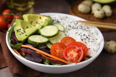 Delicious poke bowl with vegetables, avocado and mesclun on textured table, closeup