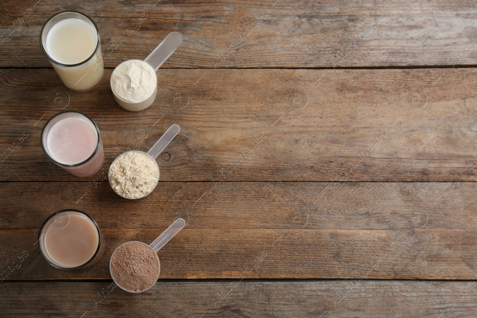 Photo of Protein shakes and powder on wooden table, flat lay. Space for text