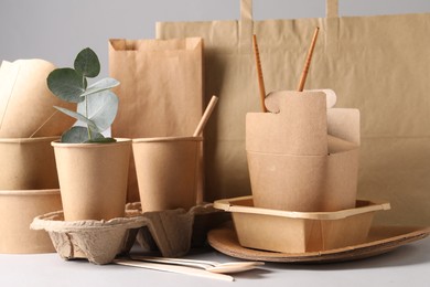 Photo of Eco friendly food packaging. Paper containers, tableware, bag and eucalyptus branch on white table