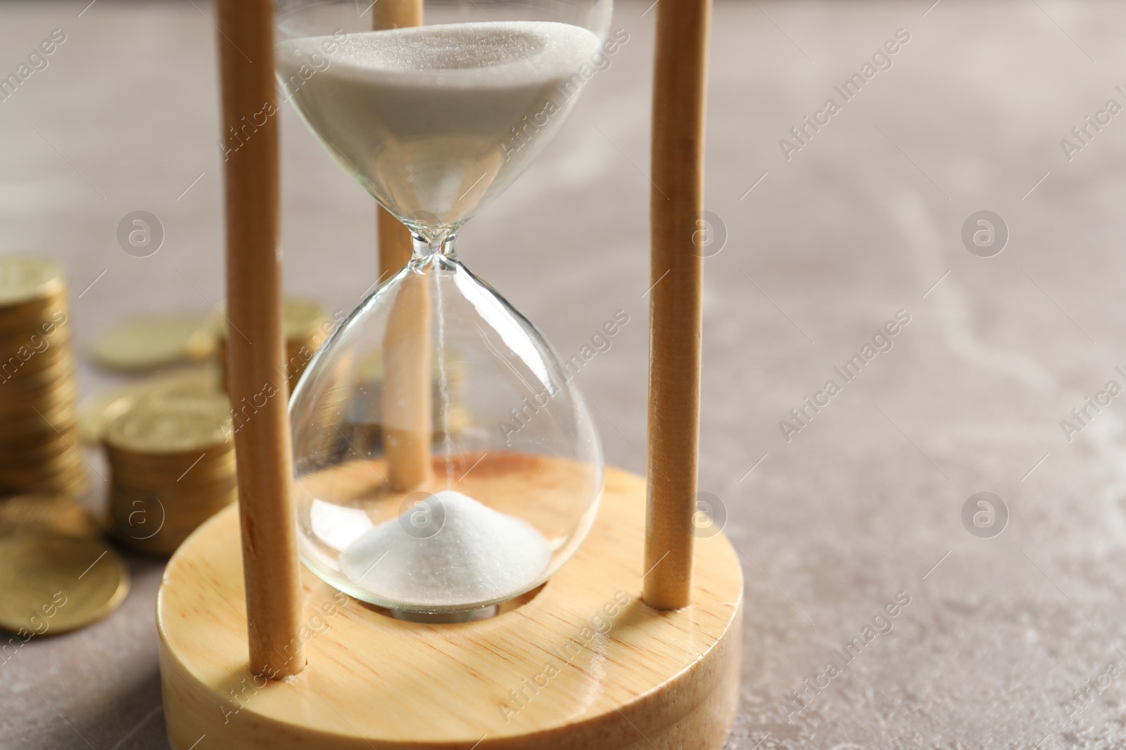 Photo of Hourglass with flowing sand and coins on table. Time management