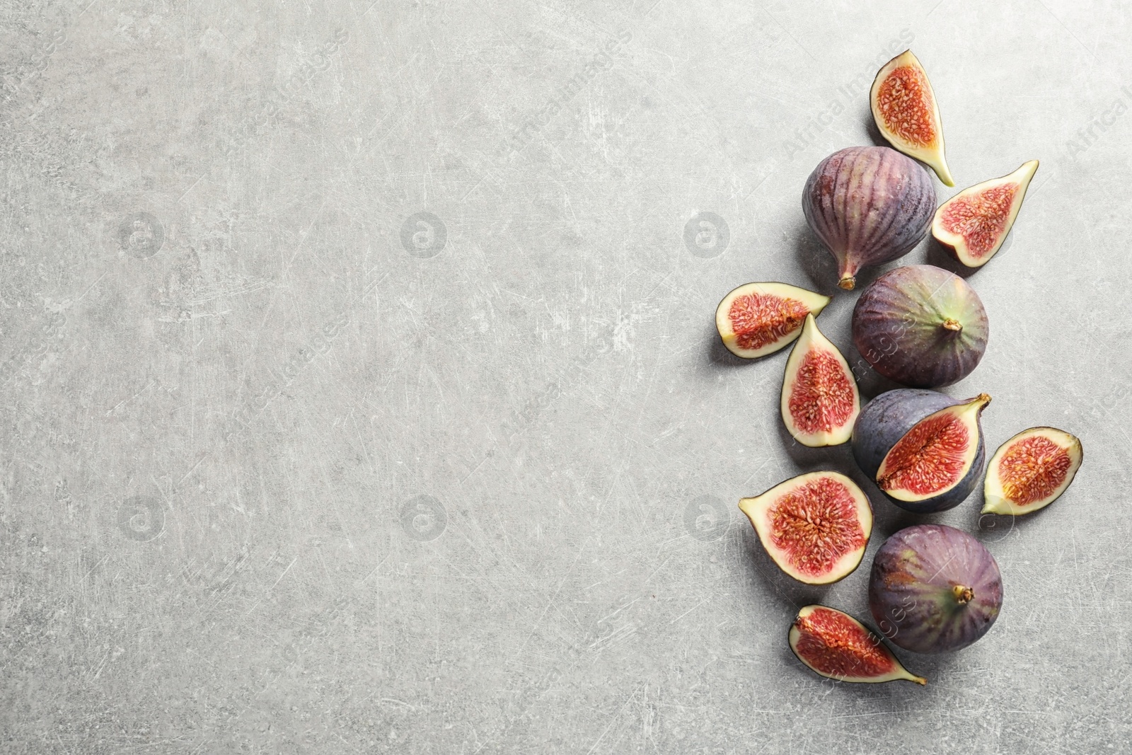 Photo of Flat lay composition with whole and cut purple figs and space for text on gray background