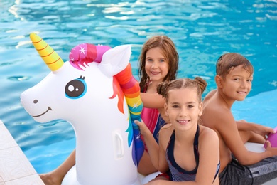 Photo of Happy children on inflatable unicorn in swimming pool