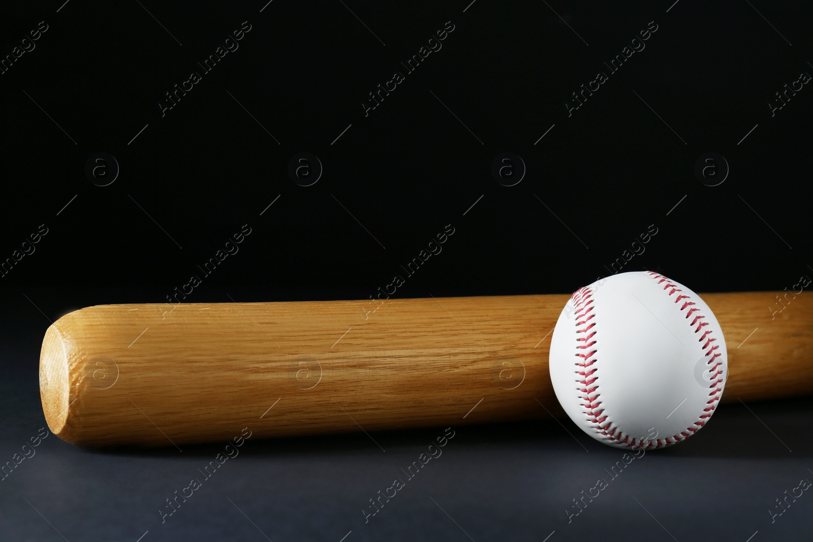 Photo of Wooden baseball bat and ball on black background, space for text. Sports equipment