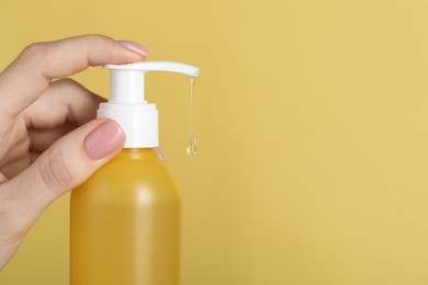 Photo of Woman using cleansing gel on pale yellow background, closeup. Space for text