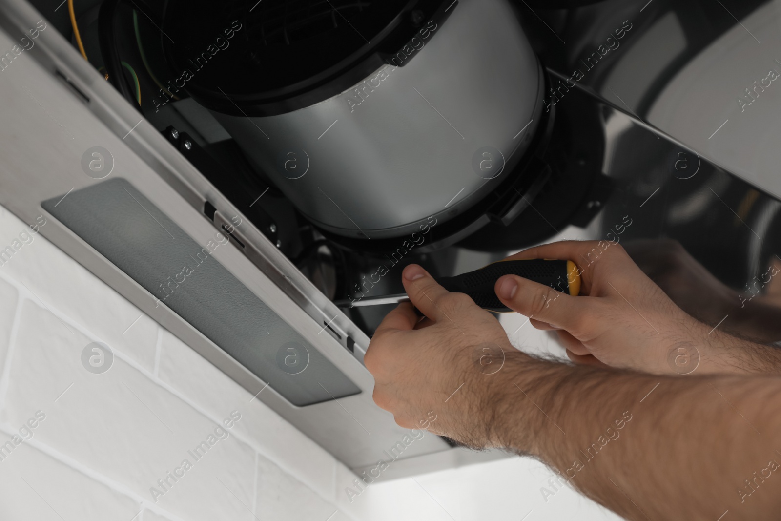 Photo of Worker repairing modern cooker hood indoors, closeup