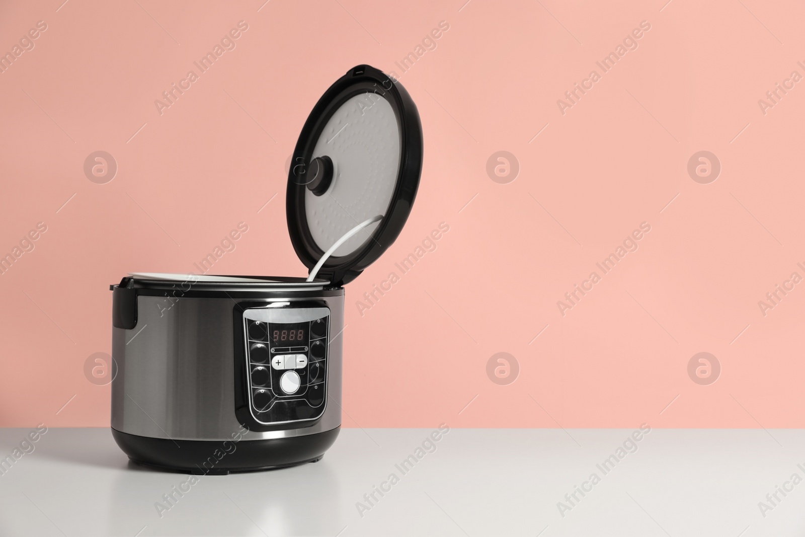 Photo of Modern electric multi cooker on table against color background. Space for text