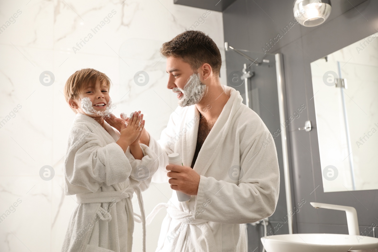 Photo of Dad applying shaving foam onto son's face in bathroom