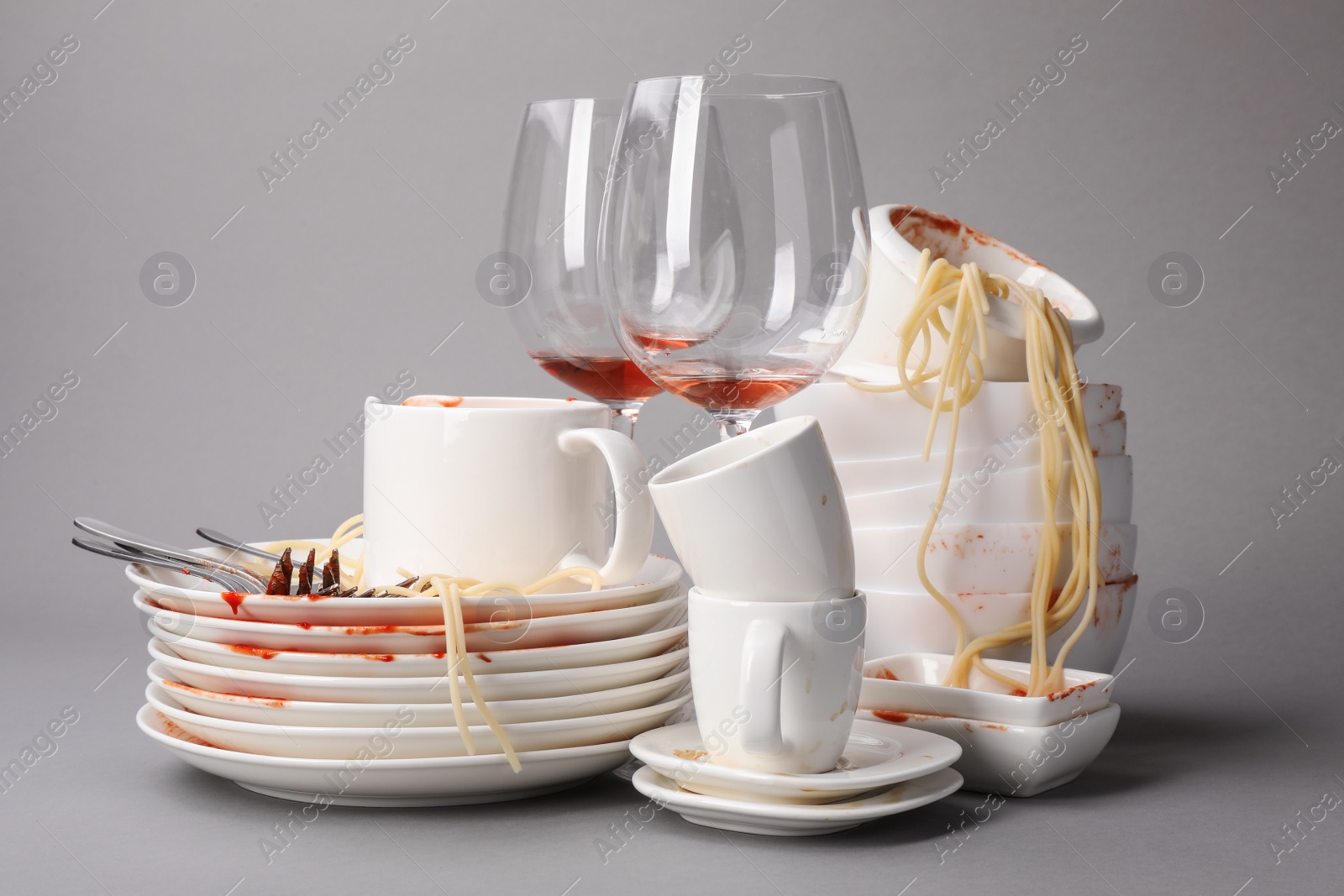 Photo of Set of dirty dishes with spaghetti leftovers on grey background