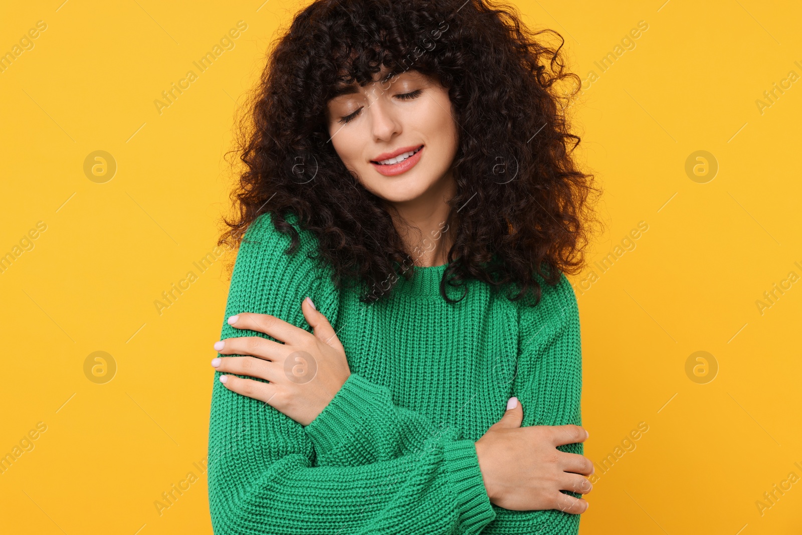 Photo of Happy young woman in stylish green sweater on yellow background