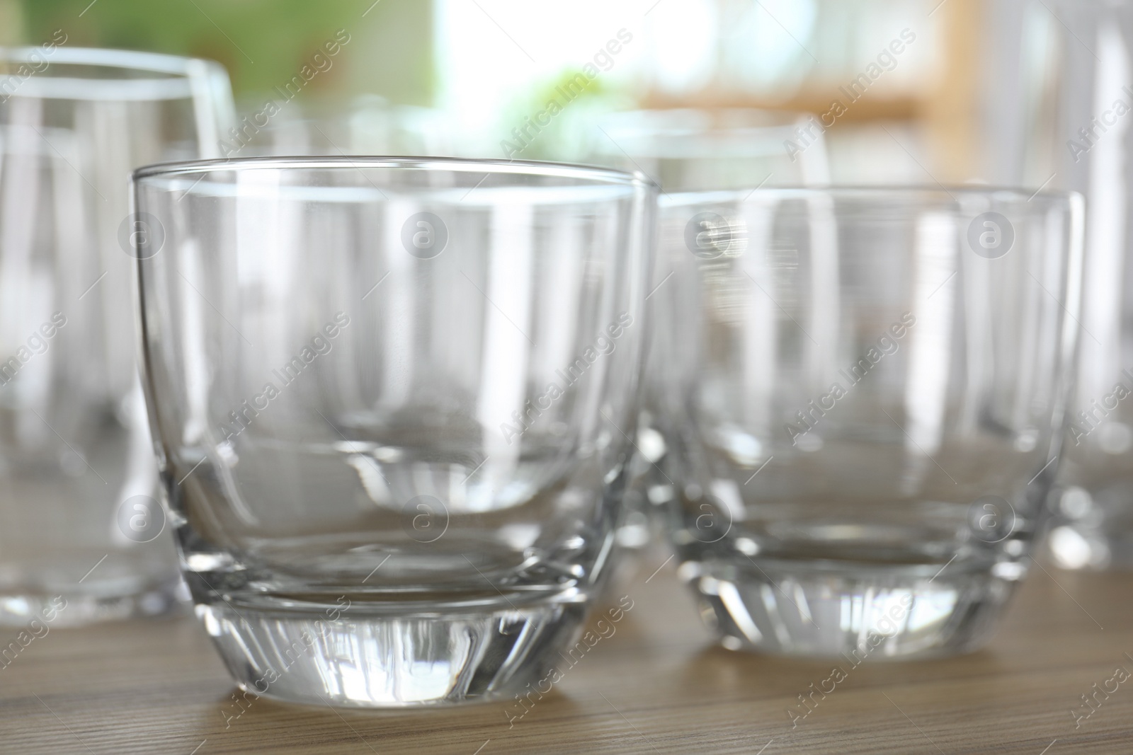 Photo of Empty glasses on wooden table against blurred background