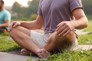 Photo of People practicing yoga in park outdoors, closeup. Lotus pose