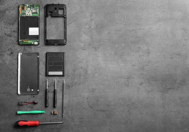 Photo of Disassembled mobile phone and repair tools on table, flat lay. Space for text