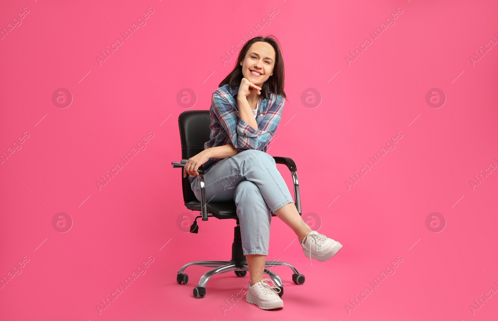 Photo of Mature woman sitting in comfortable office chair on pink background