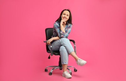 Mature woman sitting in comfortable office chair on pink background