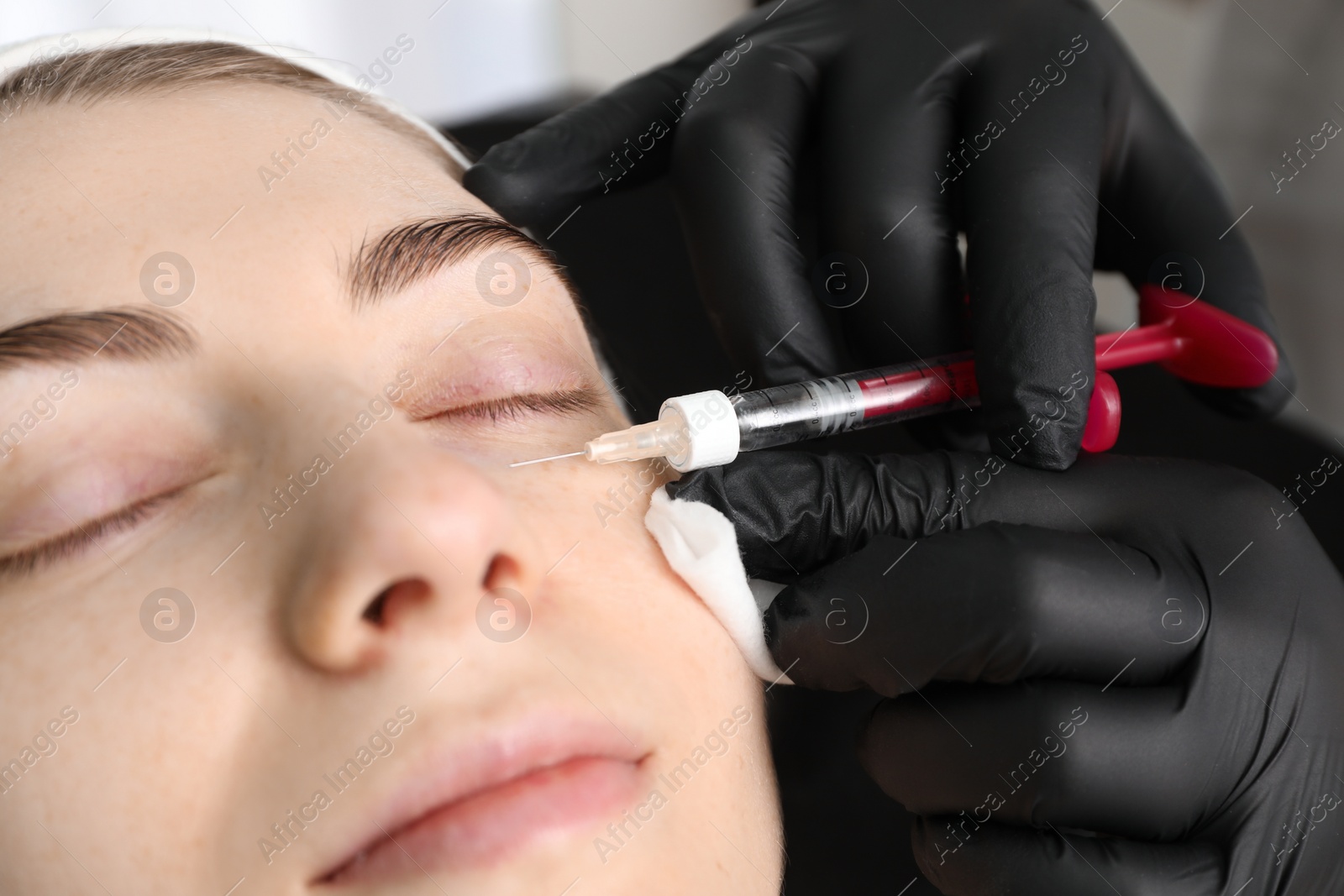 Photo of Cosmetologist giving facial injection to patient indoors, closeup. Cosmetic surgery