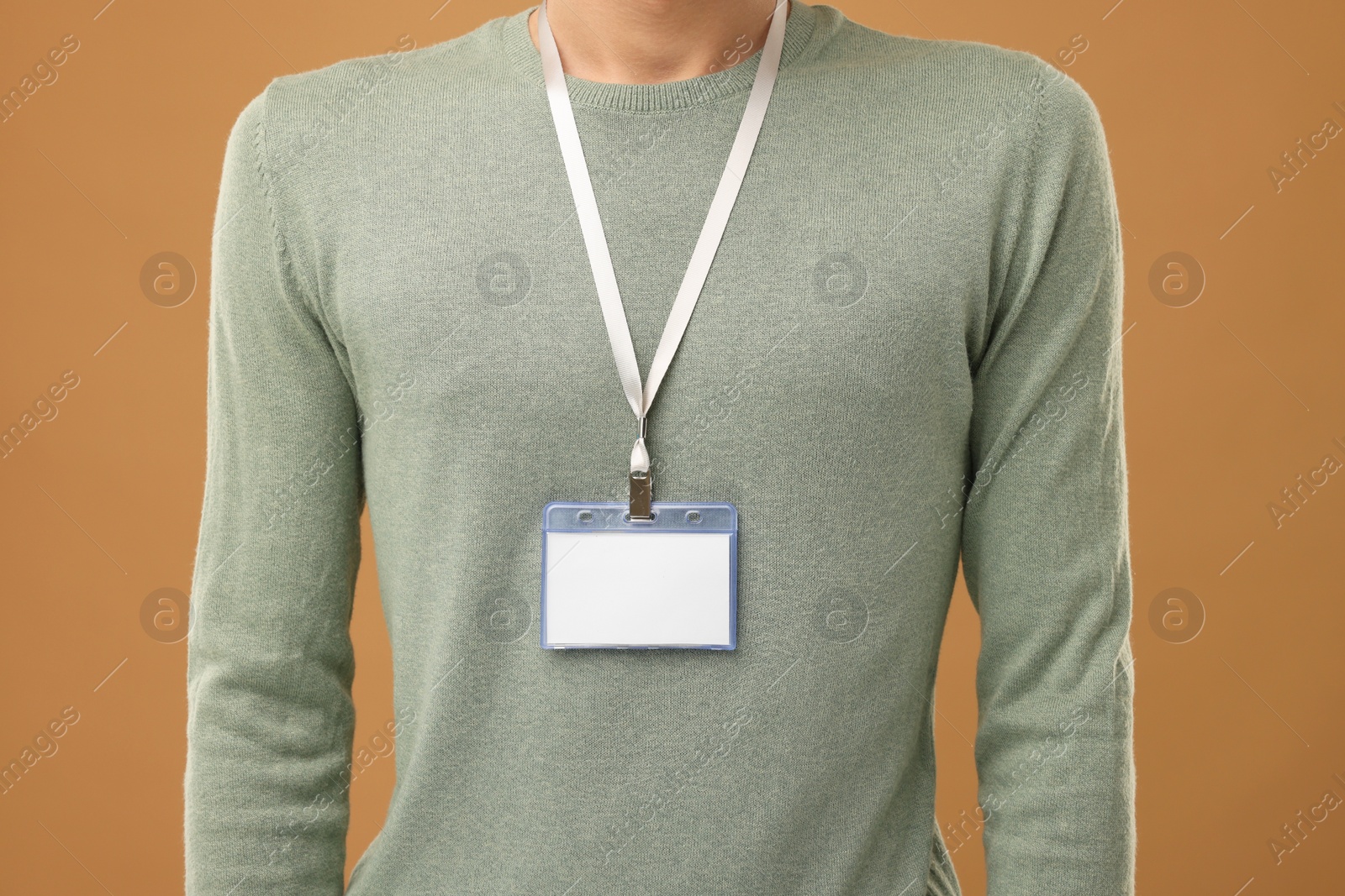 Photo of Man with blank badge on light brown background, closeup