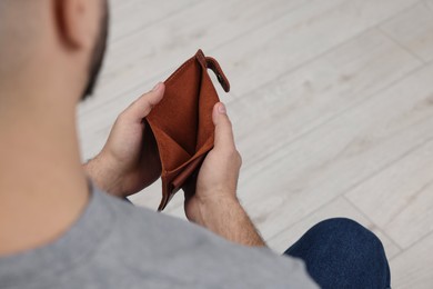 Man with empty wallet at home, closeup. Space for text