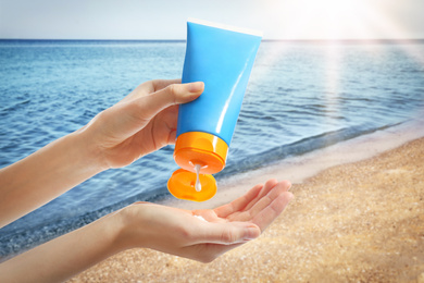 Image of Young woman applying sun protection cream near sea, closeup