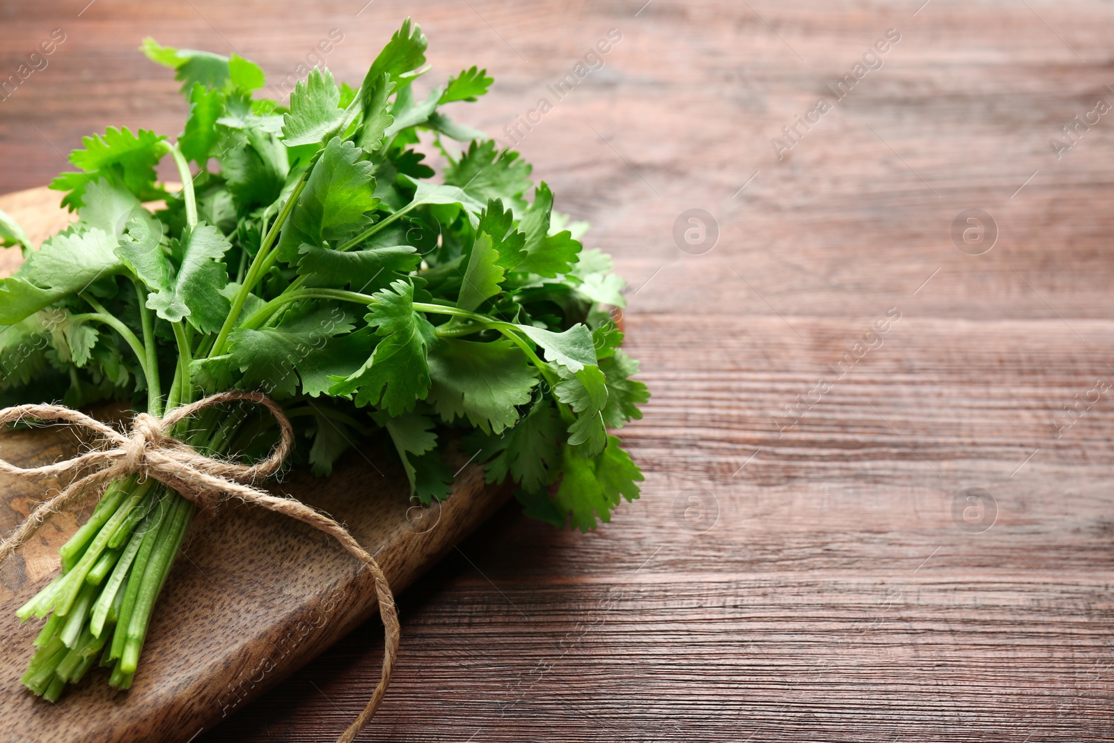 Photo of Bunch of fresh coriander on wooden table, space for text