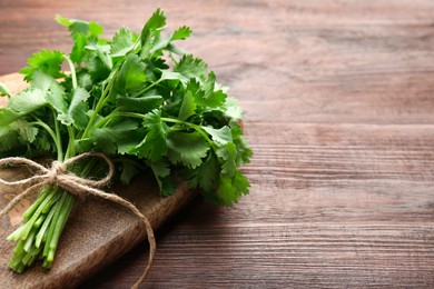 Photo of Bunch of fresh coriander on wooden table, space for text