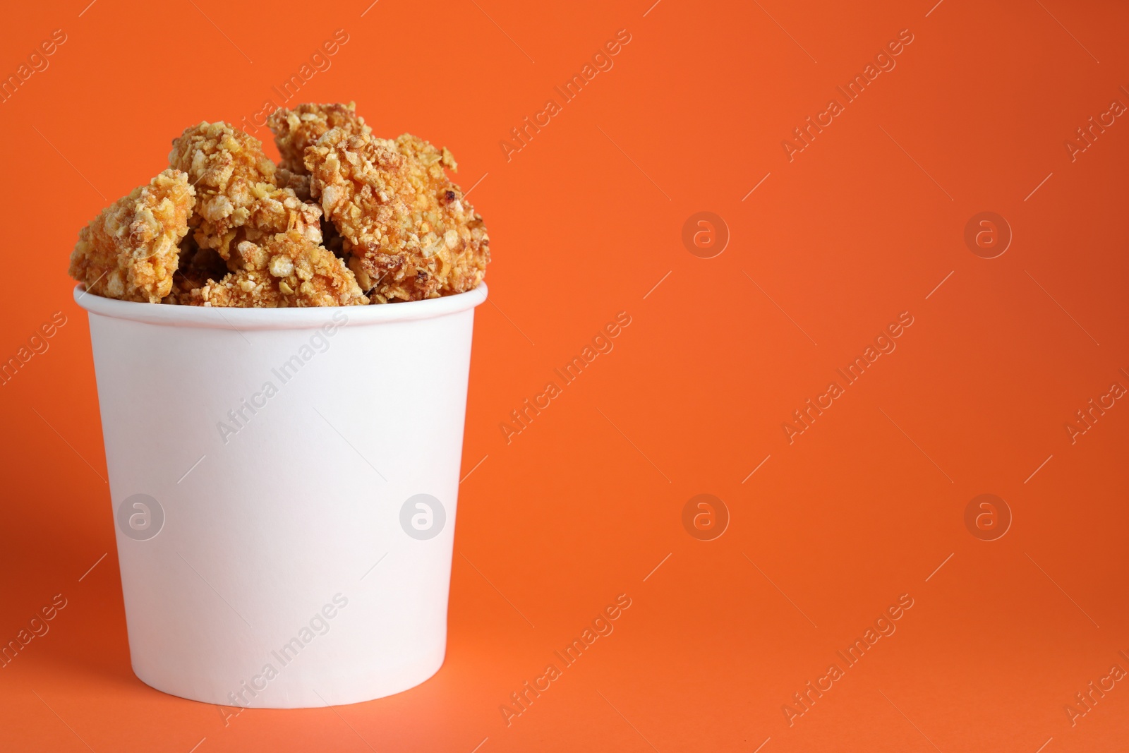 Photo of Bucket with yummy nuggets on orange background, space for text