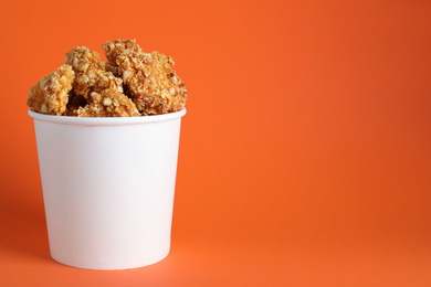 Bucket with yummy nuggets on orange background, space for text