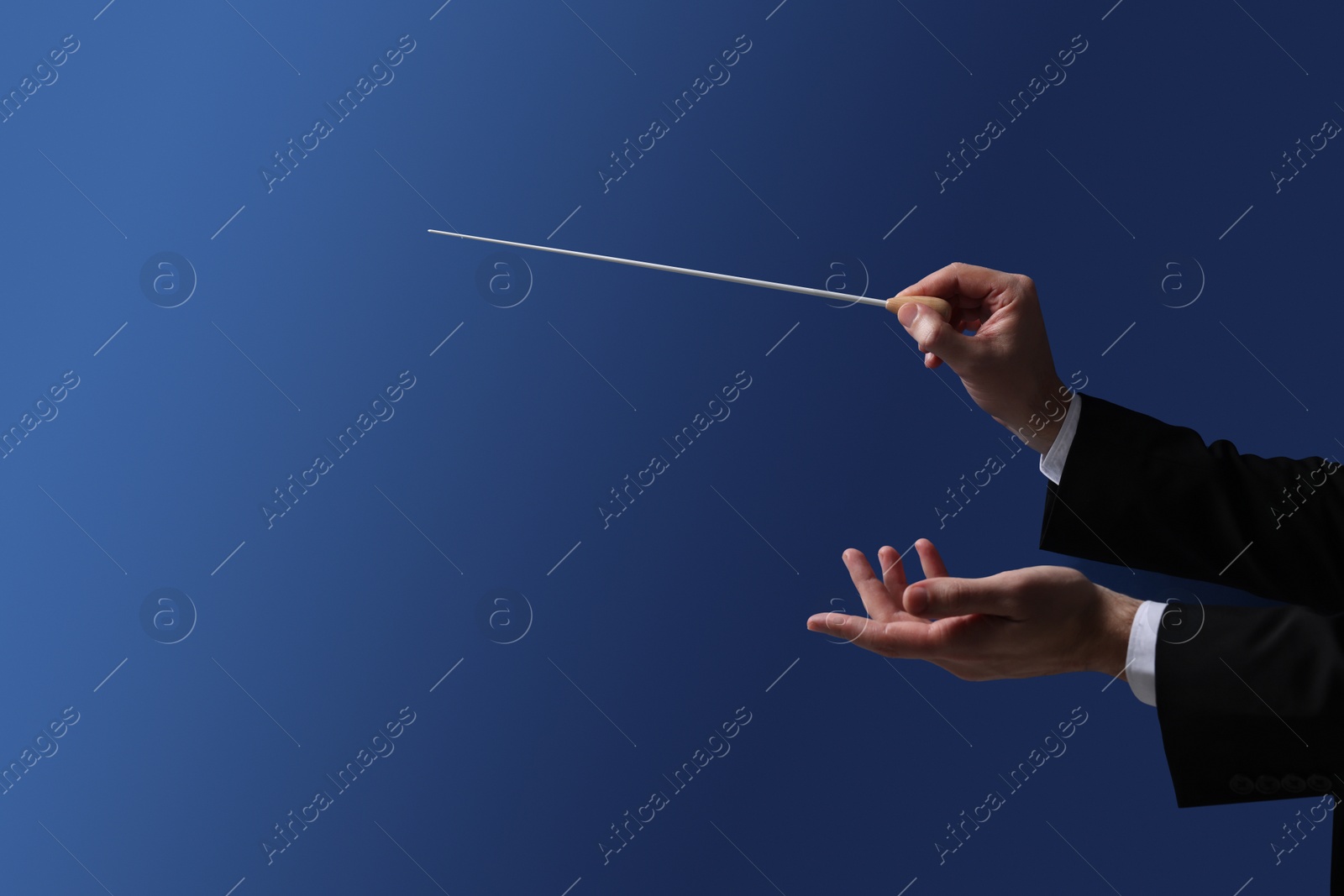 Photo of Professional conductor with baton on blue background, closeup