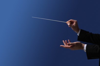 Professional conductor with baton on blue background, closeup