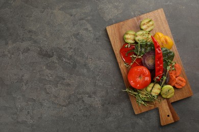 Wooden board with delicious grilled vegetables on grey table, top view. Space for text