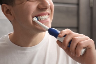 Man brushing his teeth with electric toothbrush indoors