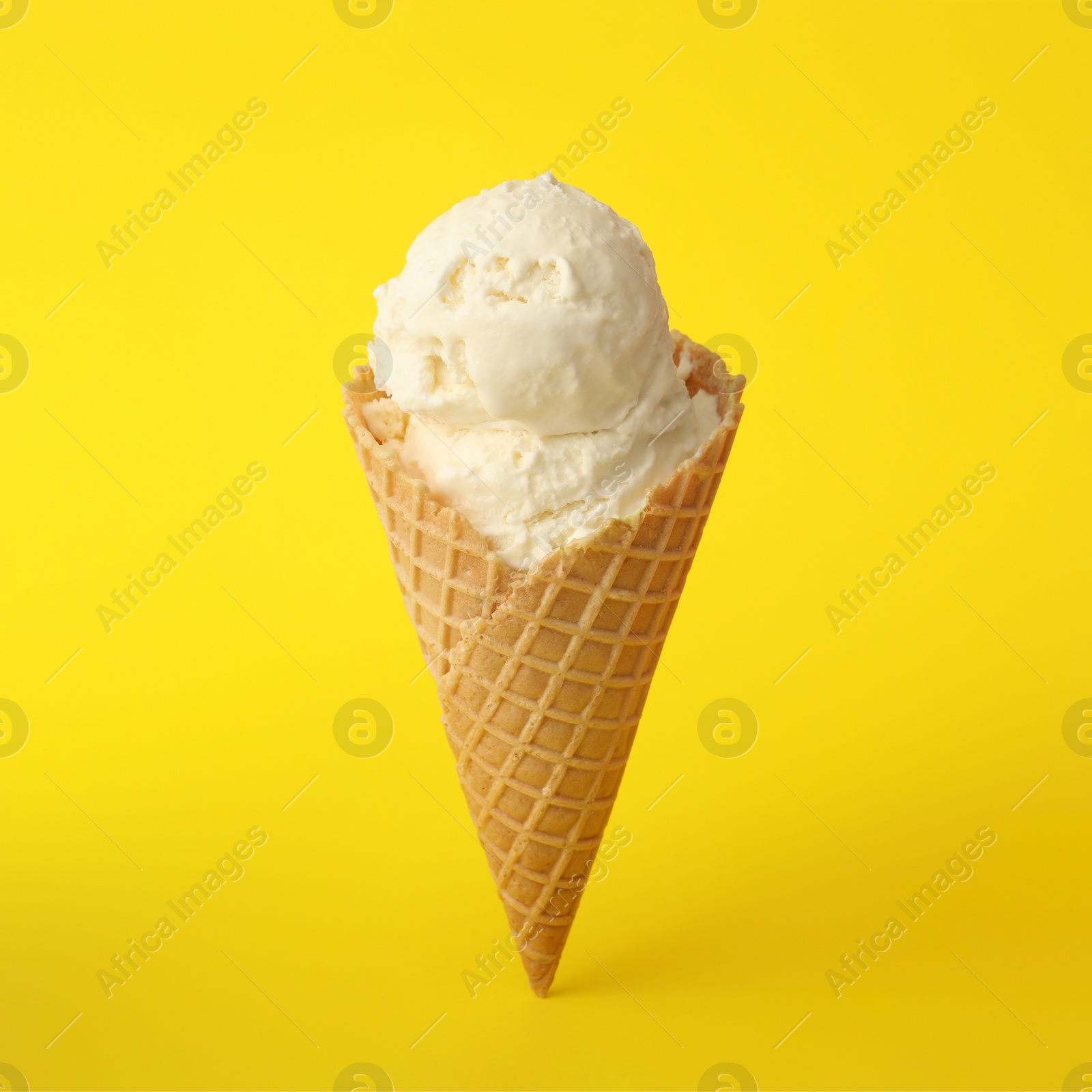 Photo of Delicious ice cream in waffle cone on yellow background