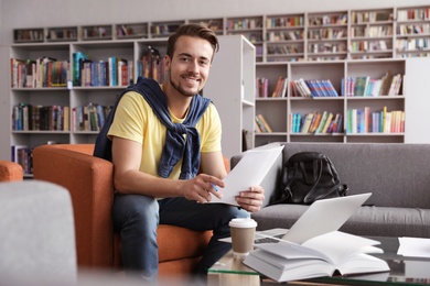 Photo of Young man studying at table in library