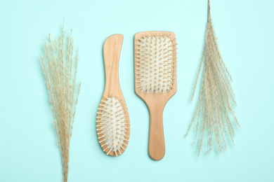 Modern hair brushes and spikelets on light blue background, flat lay