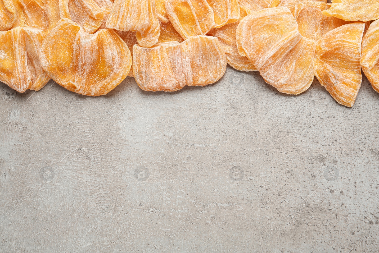 Photo of Delicious dried jackfruit slices on light grey table, flat lay. Space for text