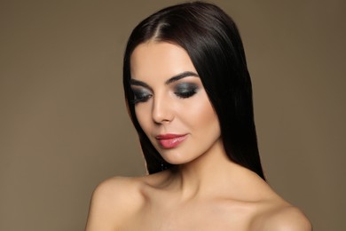 Photo of Beautiful young woman with evening makeup on brown background. Eye shadow product