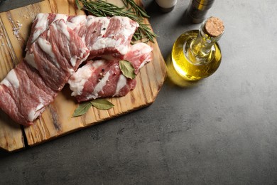 Raw ribs with herbs and spices on grey table, flat lay