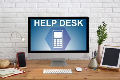 Image of Modern computer and stationery on wooden table. Help desk service