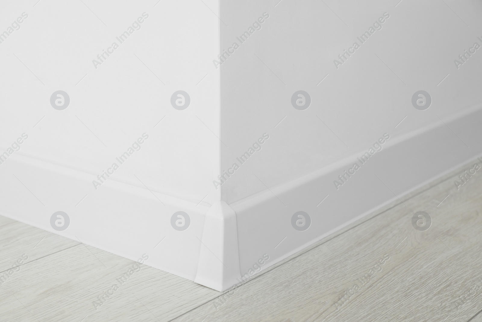 Photo of White plinth with connector on laminated floor near wall indoors, closeup