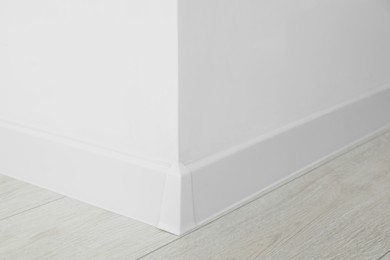 Photo of White plinth with connector on laminated floor near wall indoors, closeup