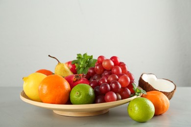 Photo of Wooden plate and different ripe fruits on grey table