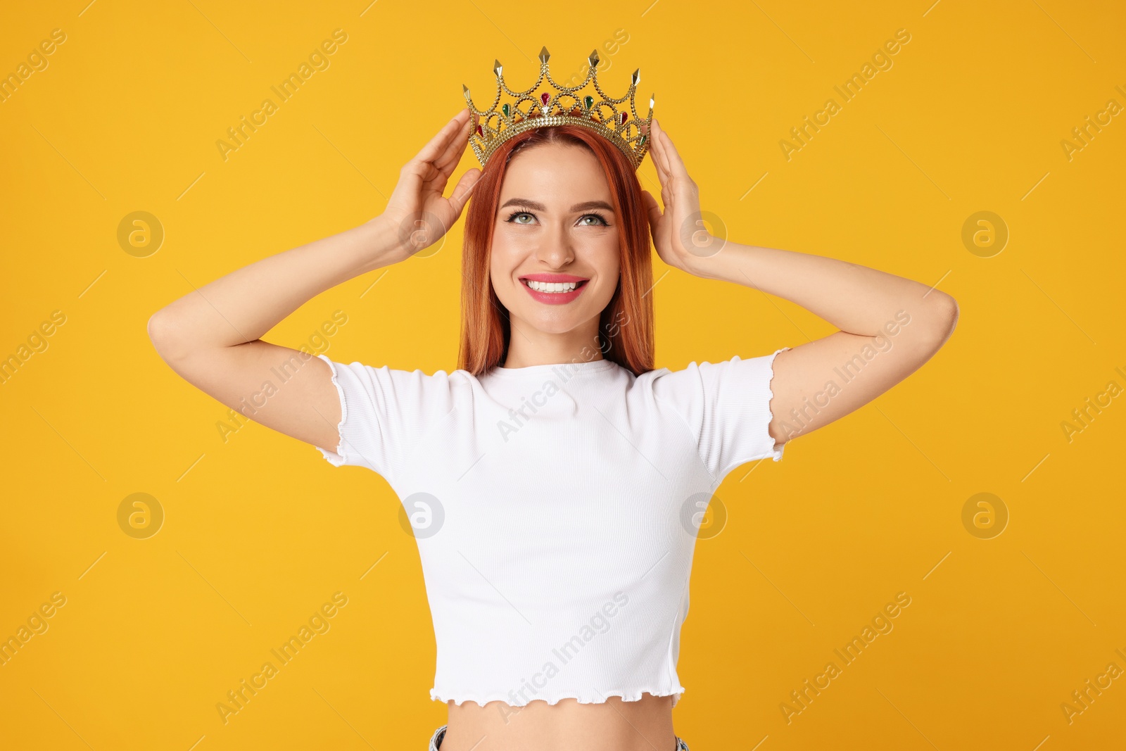 Photo of Beautiful young woman with golden crown on orange background