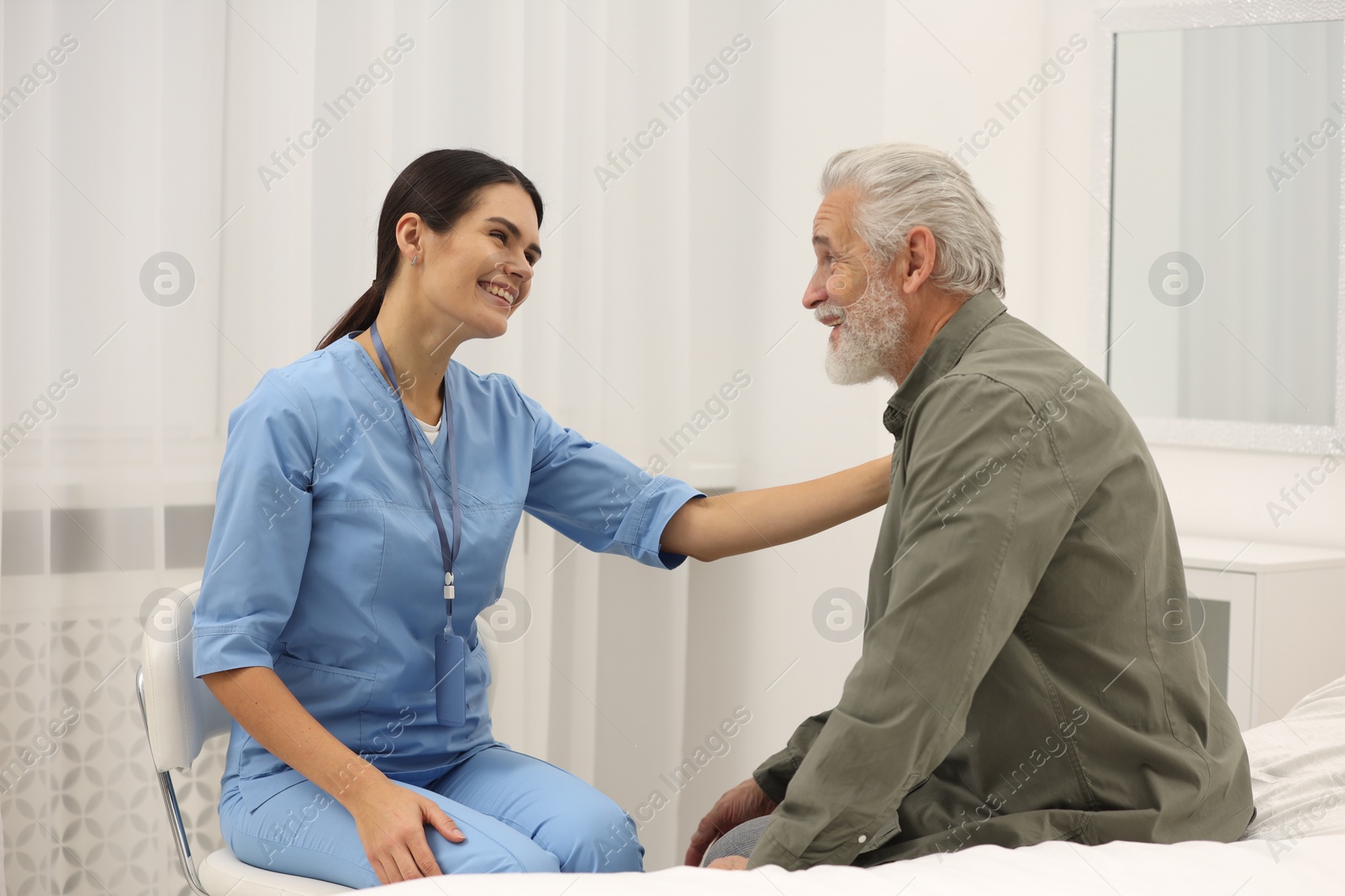 Photo of Smiling nurse supporting elderly patient in hospital