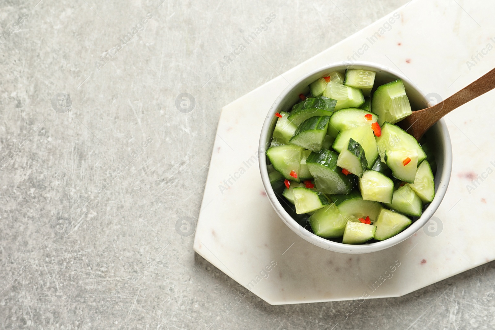 Photo of Delicious cucumber salad in bowl served on grey background, top view. Space for text