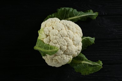 Fresh whole cauliflower on black wooden table, top view