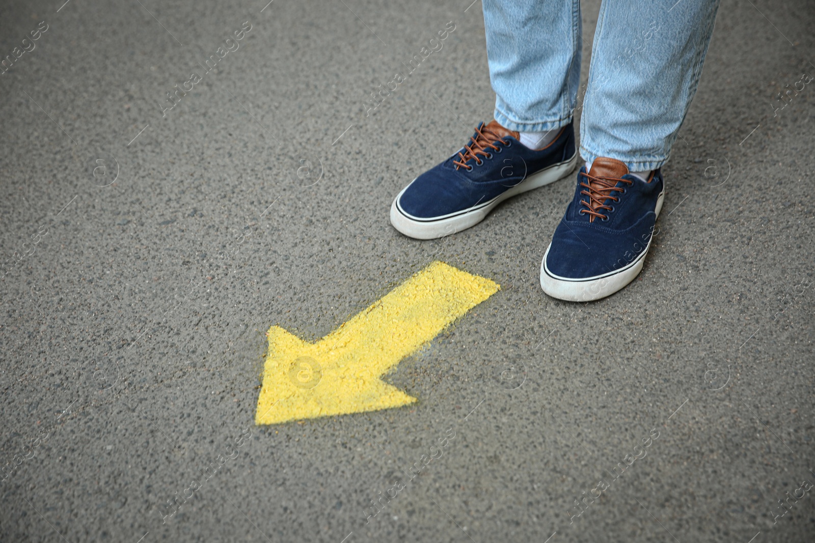 Photo of Man standing near arrow on asphalt, closeup